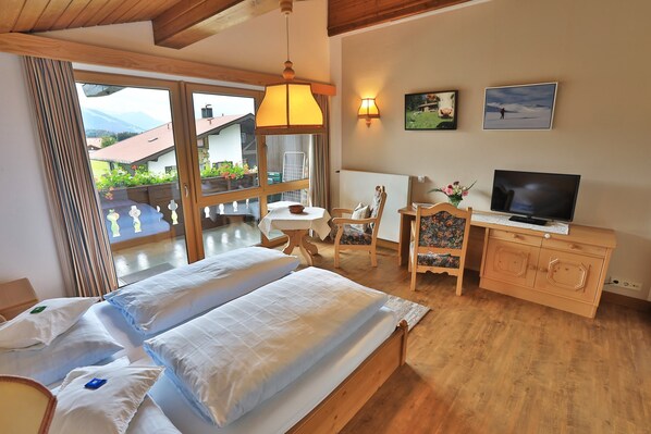 Habitación de hotel con cama, televisor, escritorio y vistas al exterior.