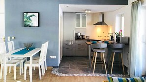 Cozinha moderna com ilha central, armários brancos e máquina de café à vista.