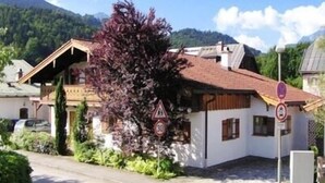 A traditional chalet with a sloped roof, wooden exterior, and a small balcony. - Ferienwohnung für 3 Personen (Berchtesgaden)