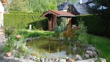 Ein friedlicher Garten mit Teich, umgeben von einem Steinrand und üppigem Grün.