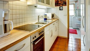 A modern kitchen with white cabinets, a stainless steel range hood, a microwave, and a built-in oven. - Ferienwohnung für 3 Personen (Berchtesgaden)