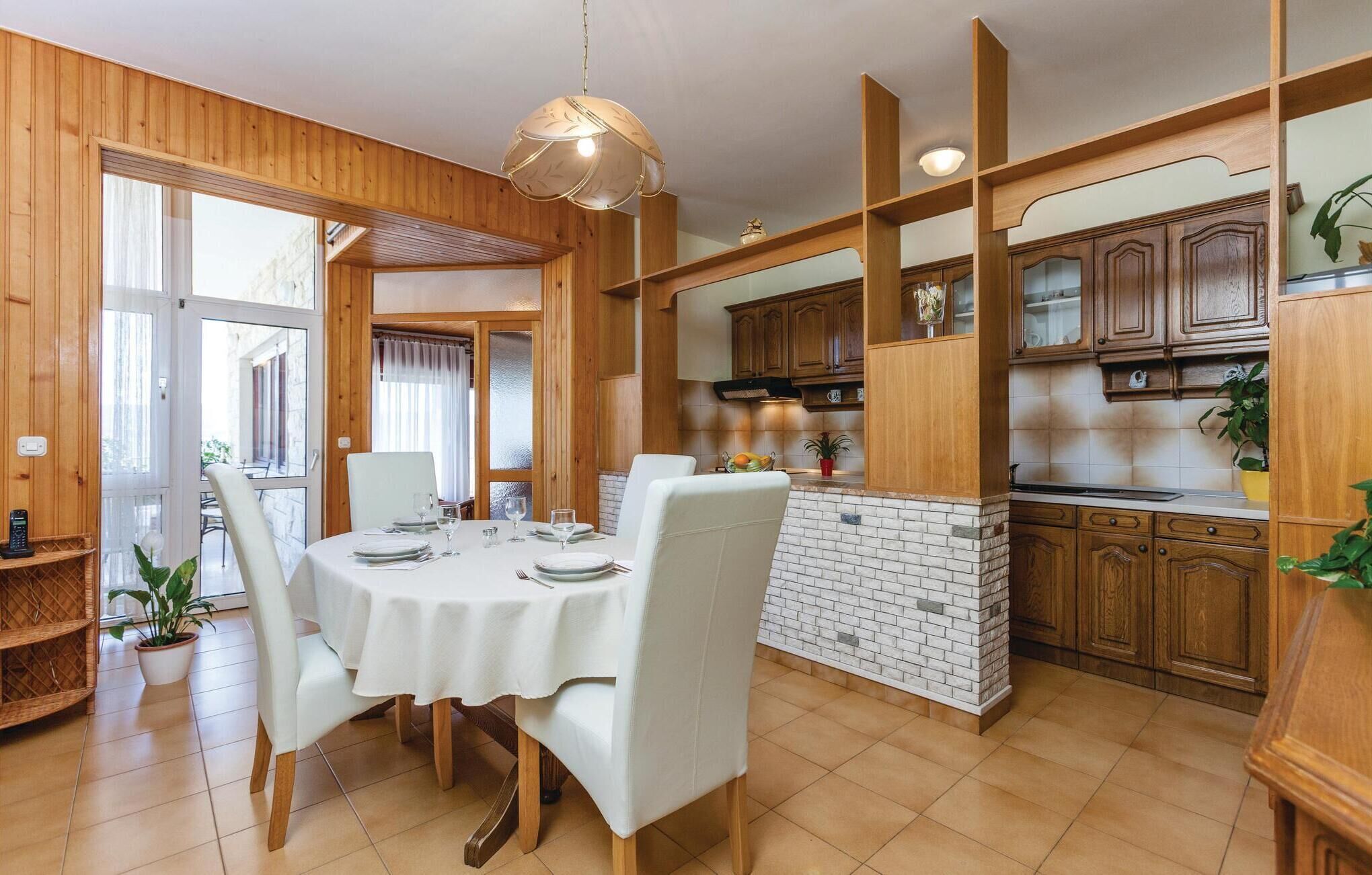 A dining area with a round table, white chairs, and a brick backsplash.