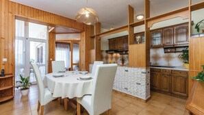 Un comedor con una mesa redonda, sillas blancas y un backsplash de ladrillo.