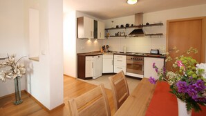 Una cocina moderna con armarios blancos, una mesa de comedor de madera y un florero con flores.