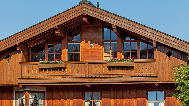 Un chalet en bois doté d’un toit à forte pente, de grandes fenêtres et de balcons ornés de jardinières.
