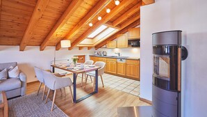 Une cuisine moderne avec des meubles en bois, un réfrigérateur en acier inoxydable et un coin repas comprenant une table et des chaises.