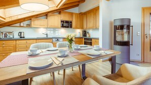 Une cuisine moderne avec des meubles en bois, une table à manger pour quatre personnes et un appareil à café encastré.