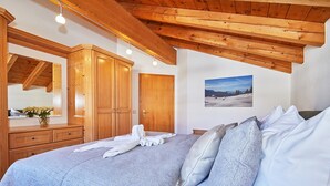 Une chambre à coucher avec un grand lit, une armoire en bois et un tableau accroché au mur.