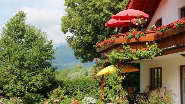 A garden with a wooden balcony, potted plants, and outdoor furniture. - I. Vacation apartment 72sqm, terrace, 1 bedroom, living room/bedroom, Loferer view (Ruhpolding)