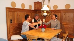 A wooden dining table with four chairs, a vase with red flowers, and a hanging light fixture. - I. Vacation apartment 72sqm, terrace, 1 bedroom, living room/bedroom, Loferer view (Ruhpolding)