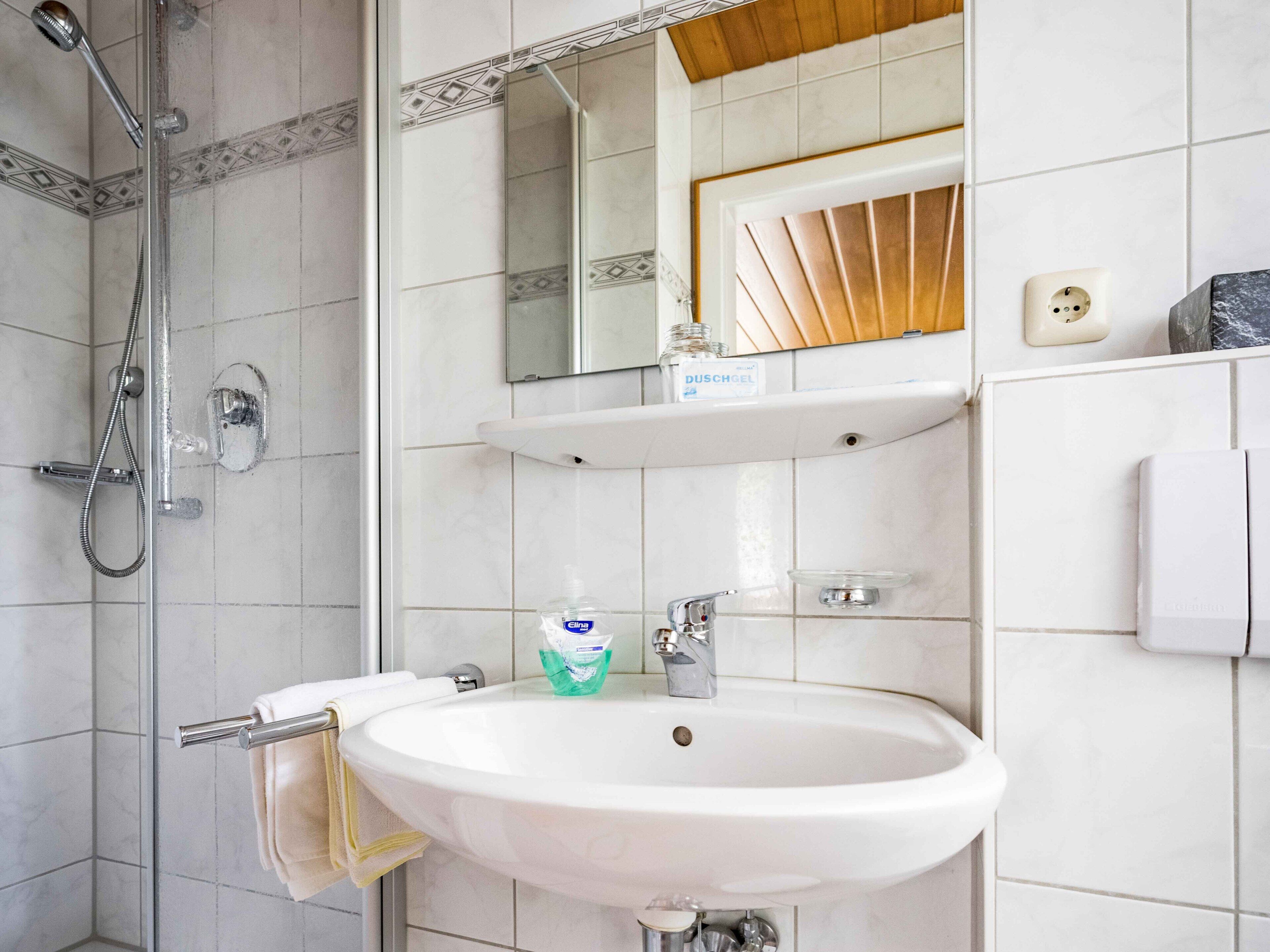 A bathroom with a shower, sink, and mirror.