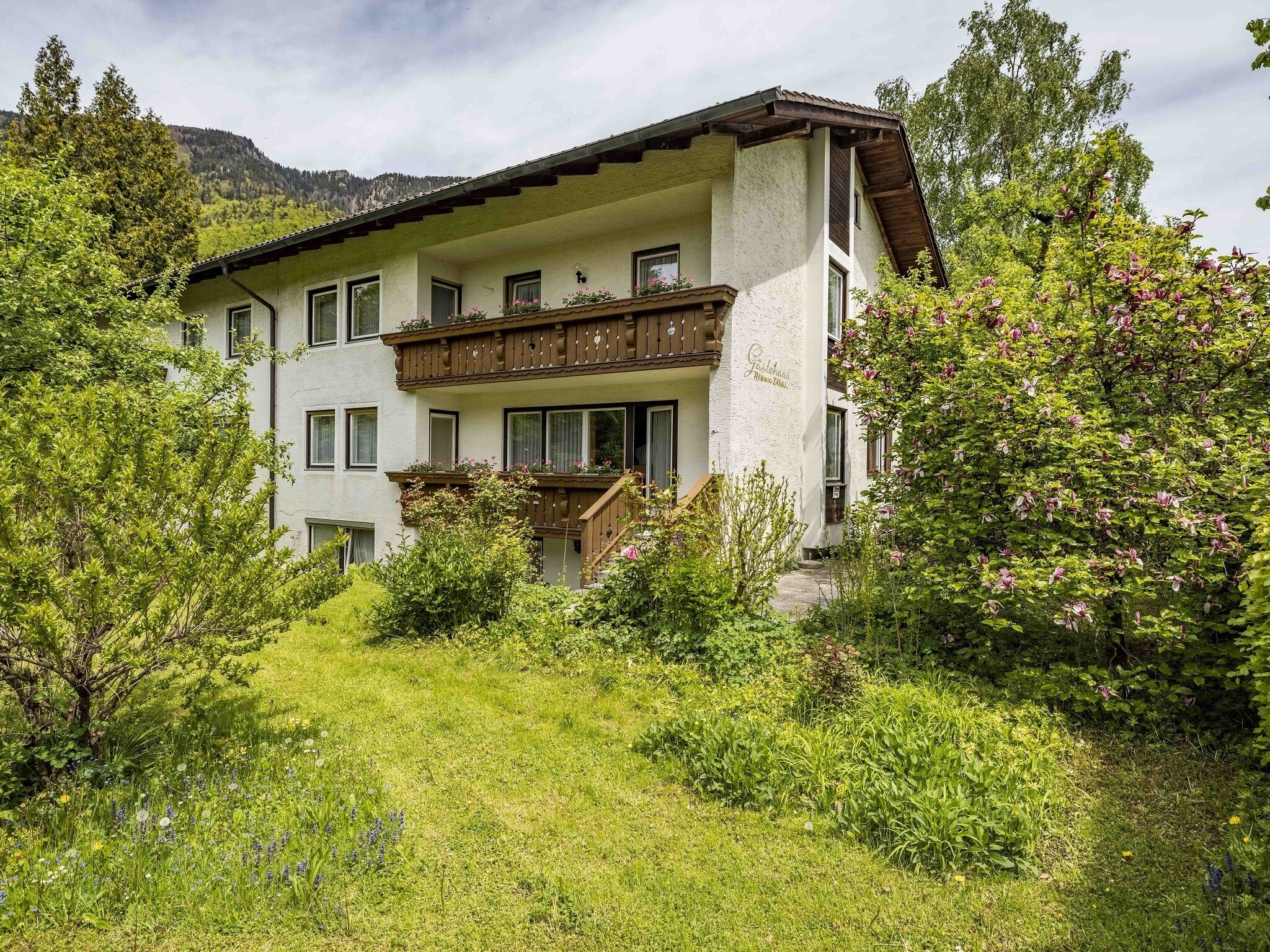 Un immeuble de deux étages doté d’un balcon et d’un jardin à l’avant.