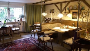 Un área de comedor con muebles de madera, una alfombra estampada y vistas al exterior a través de una ventana.