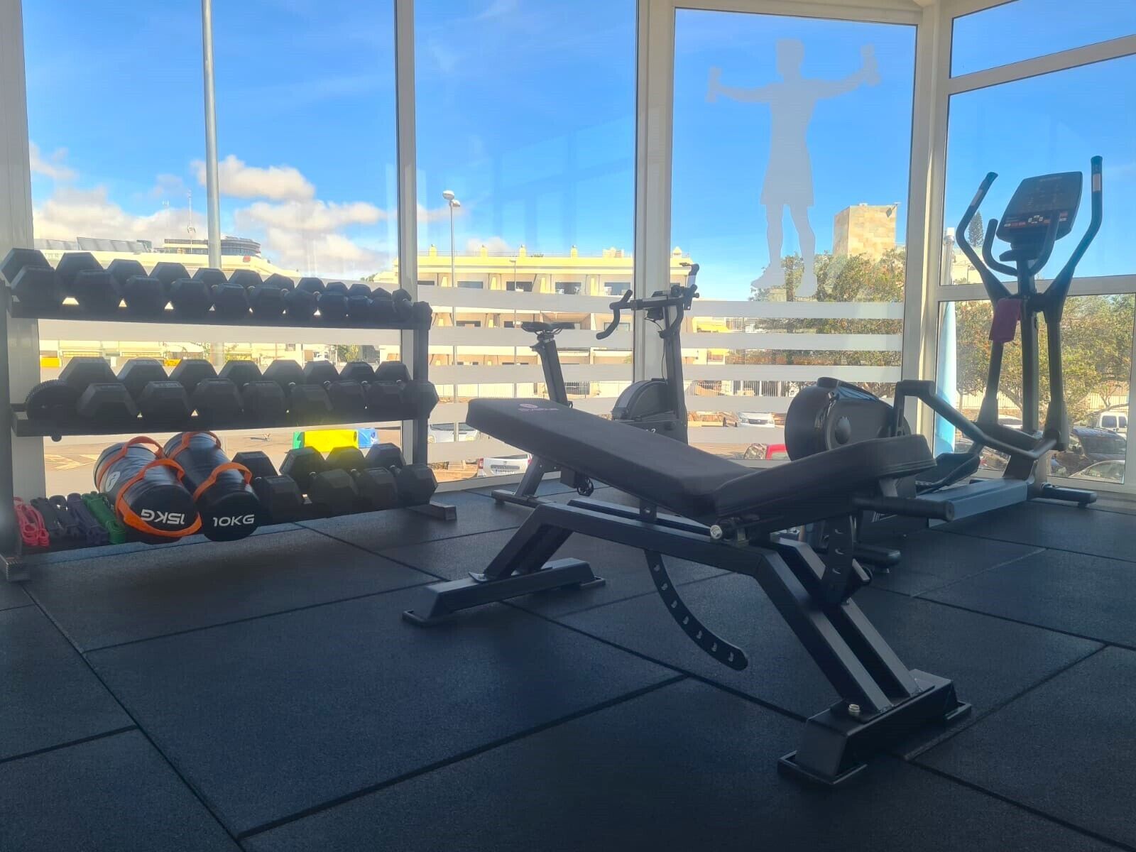 Une salle de sport équipée de machines d’exercice, d’haltères et d’un banc.