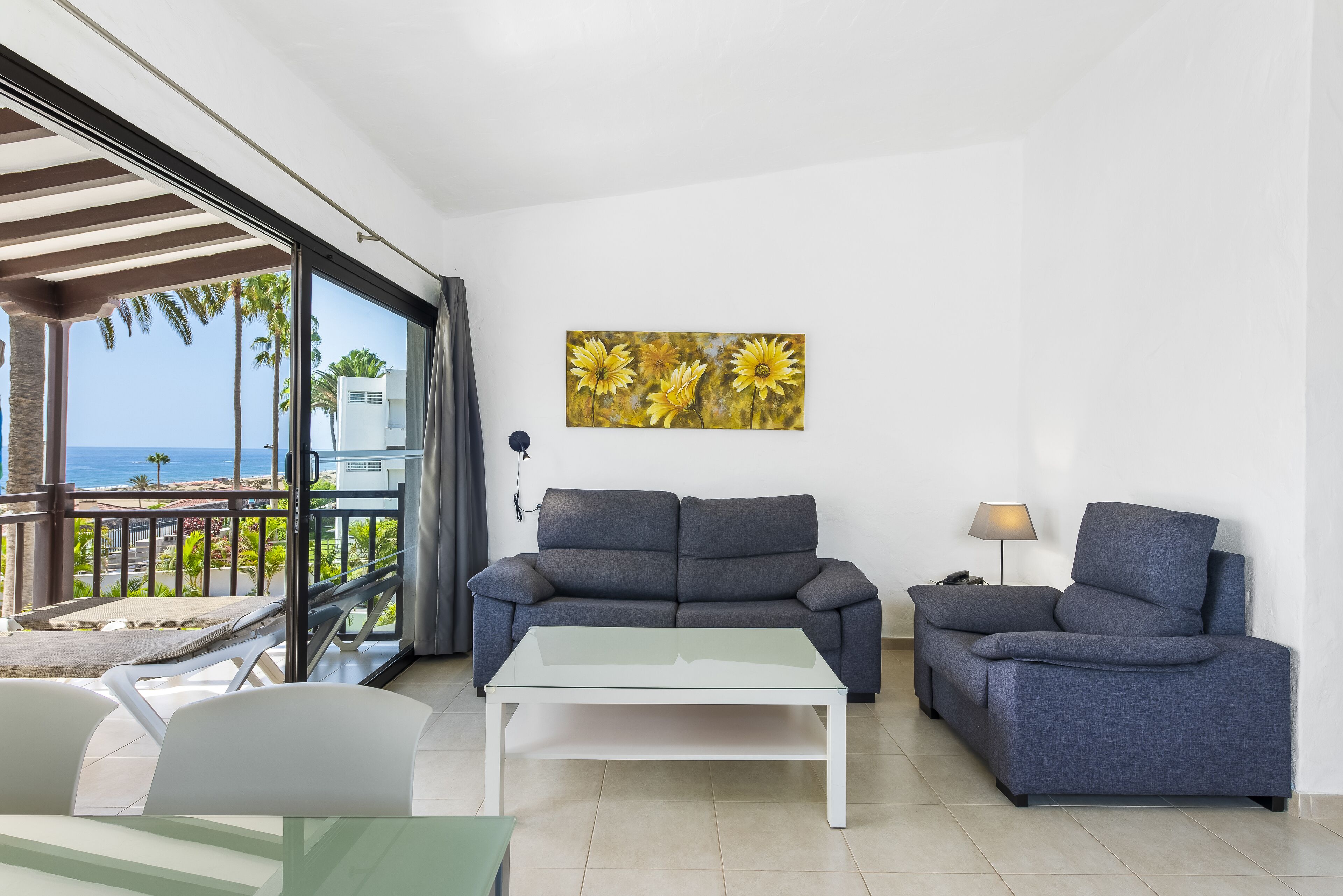Ein modernes Wohnzimmer mit einer Couch, einem Couchtisch und Blick auf den Ozean durch große Fenster.
