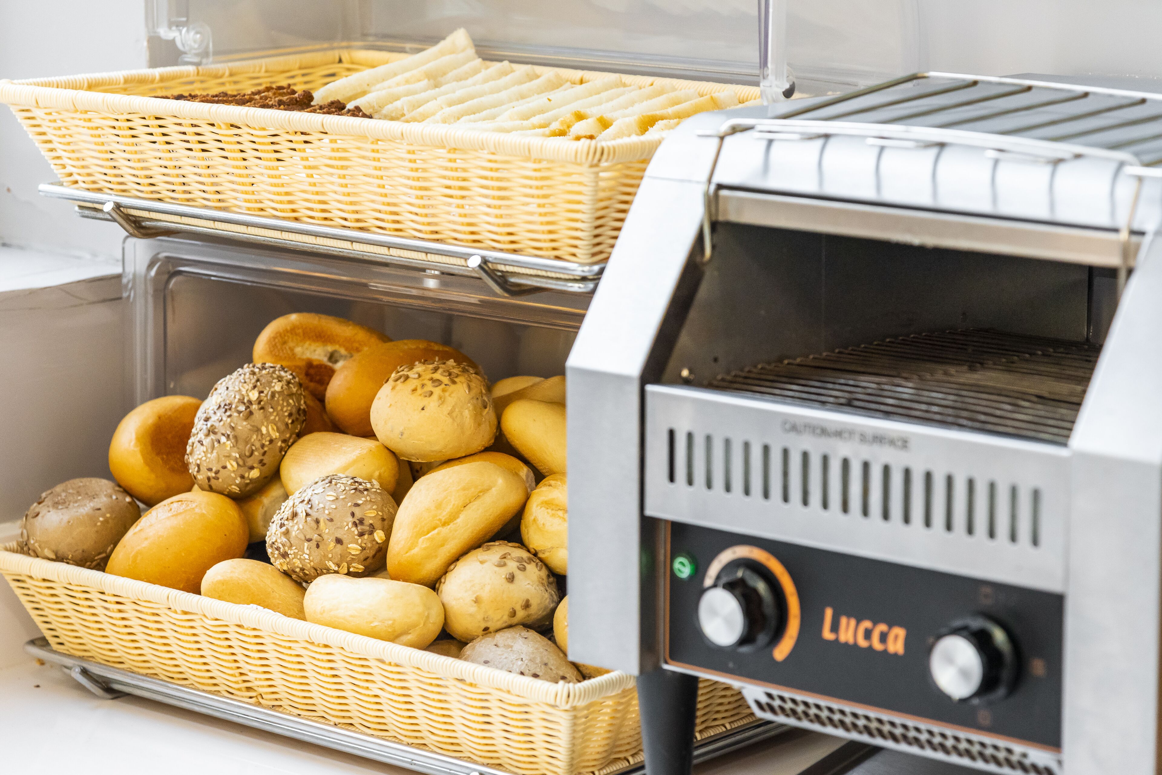 A bakery display with various baked goods in wicker baskets and a commercial toaster oven.