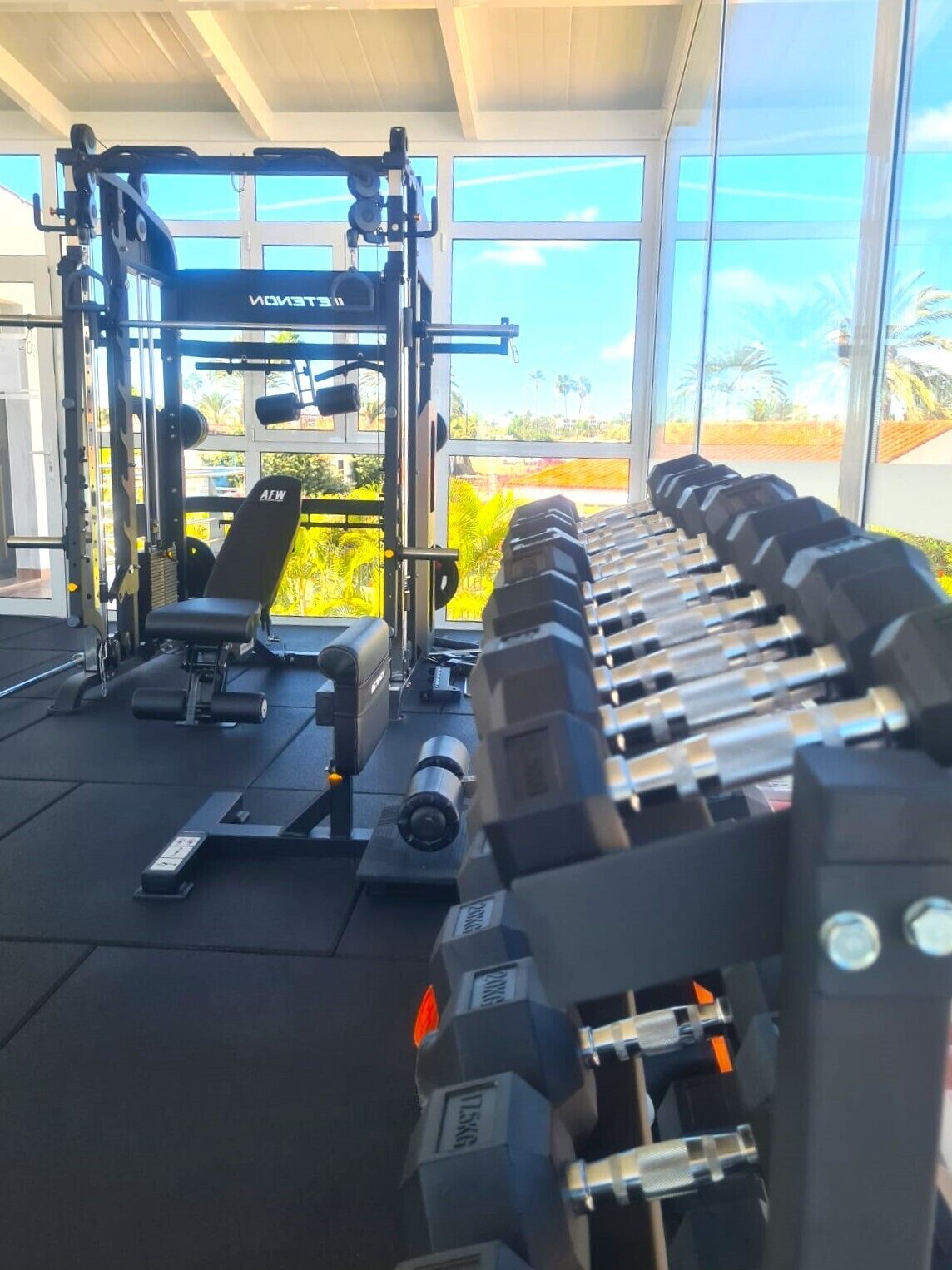 Un gimnasio con equipo de levantamiento de pesas y una banca.