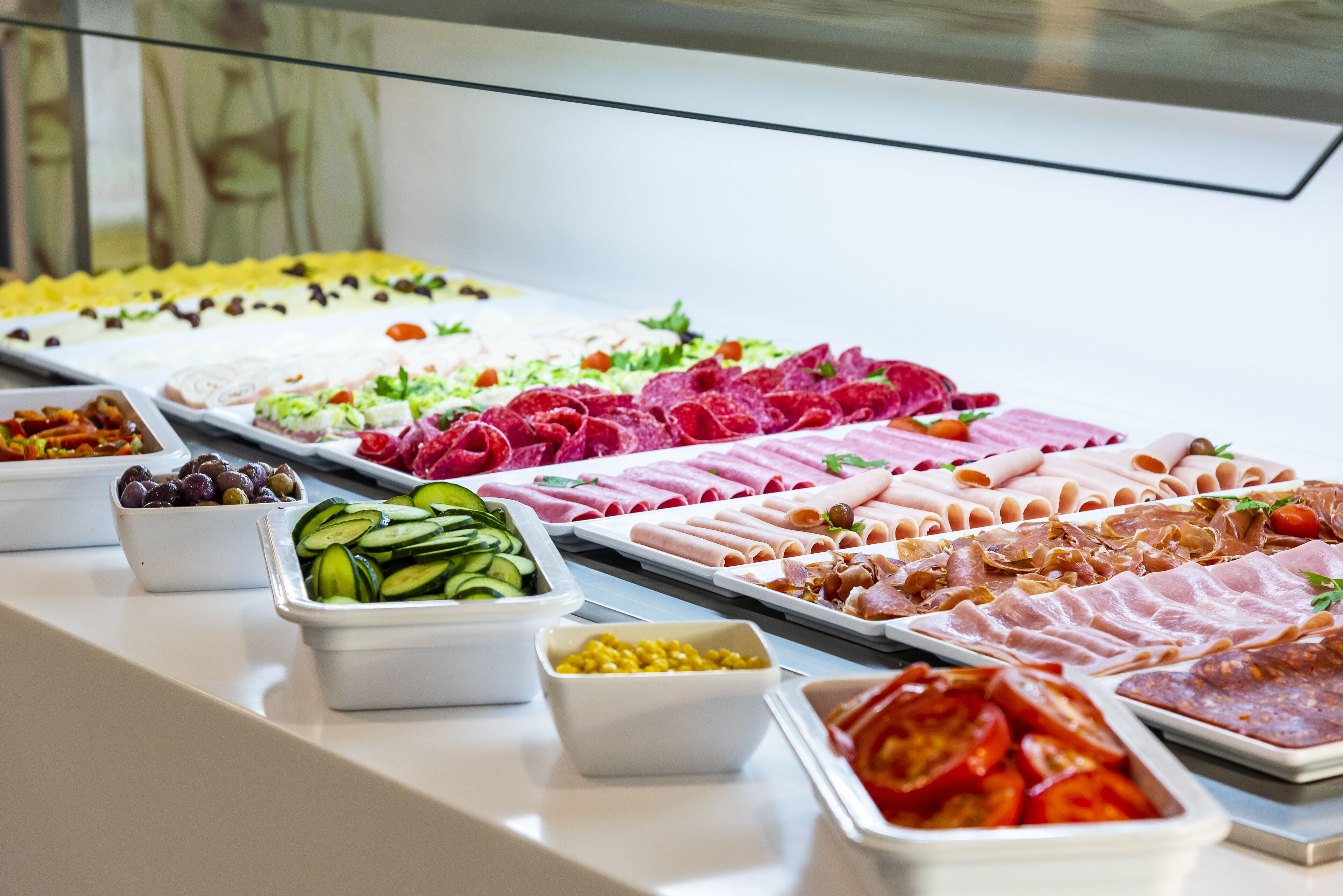 A buffet with various food options including meats, cheeses, and vegetables.