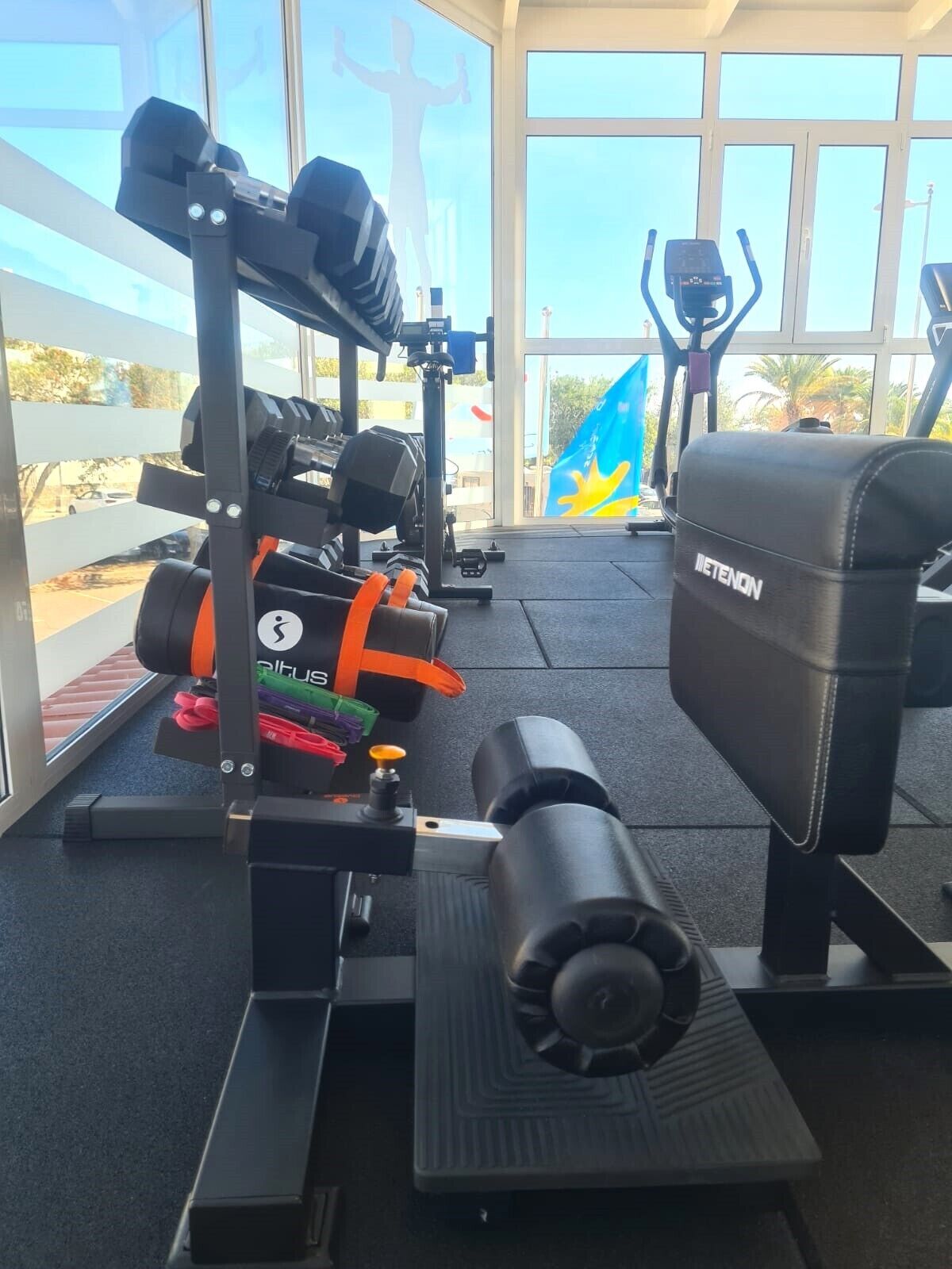 Uma academia com diversos equipamentos de ginástica, incluindo um banco prensa, halteres e uma máquina de remo.