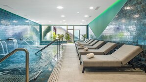 A modern indoor pool area with lounge chairs and a water feature. - Casas Pepe Apartments & Spa- Adults Only (San Bartolomé de Tirajana)