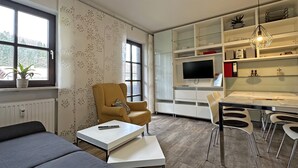 Un salon moderne comprenant un canapé, une table basse, un fauteuil jaune et un coin repas avec des chaises et une table.