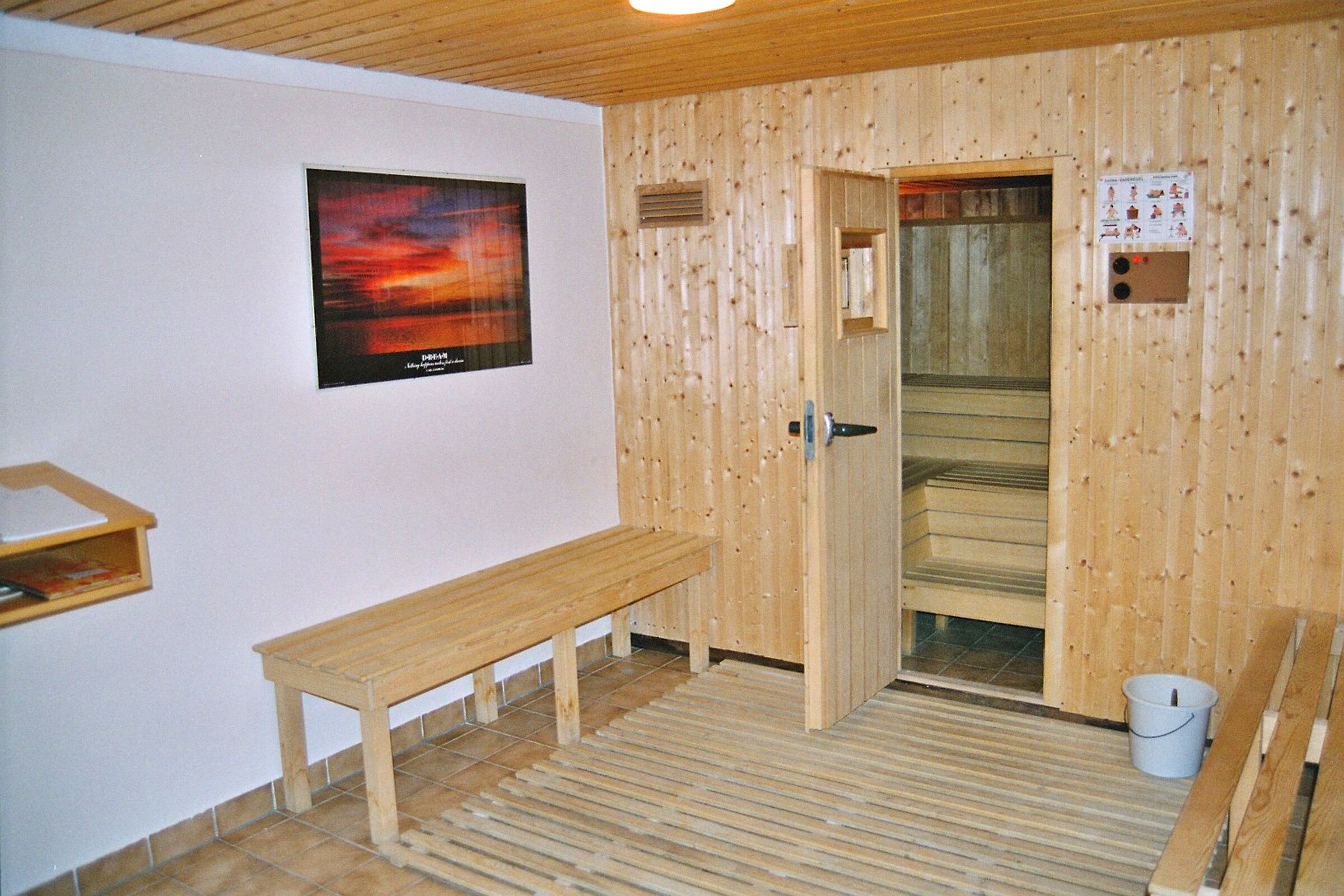 Un sauna avec des murs en bois, un banc, une porte et une affiche accrochée au mur.