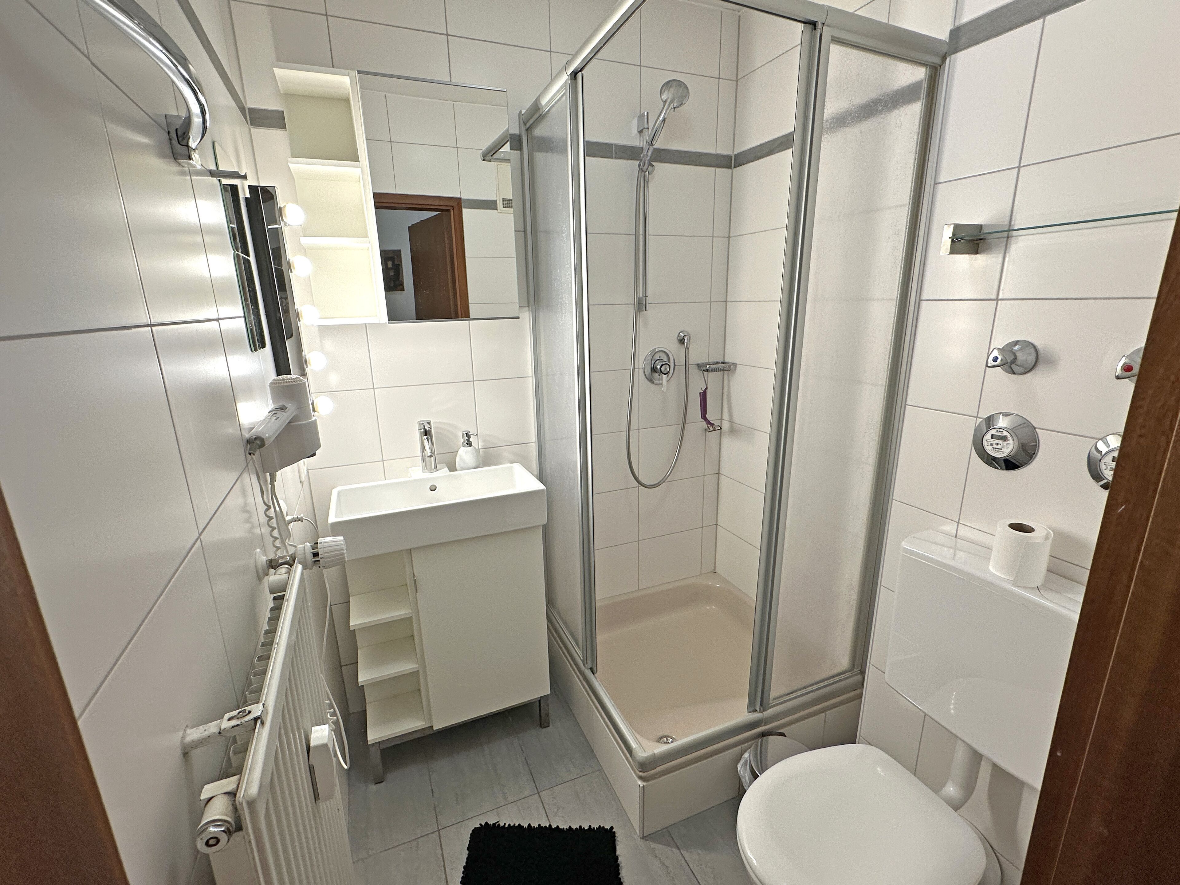 Een moderne badkamer met douche, toilet en wastafel.