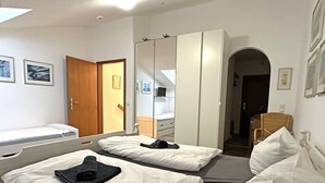 Une chambre d’hôtel avec deux lits, une armoire, un miroir et une chaise.