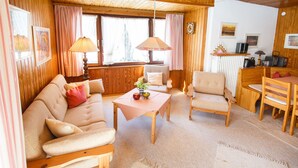 A cozy living room with a sofa, chairs, a table, and a lamp. - Apartment 2 upper floor 57sqm, balcony, kitchenette, 2 bedrooms, living room (Ruhpolding)