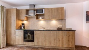 Une cuisine moderne avec des meubles en bois, un four encastré, un four à micro-ondes et un évier.