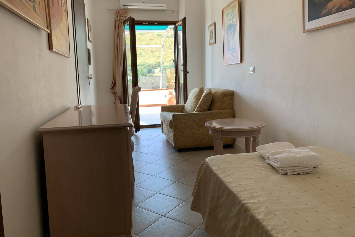 A hotel room with a bed, a small table, a sofa, and a desk.