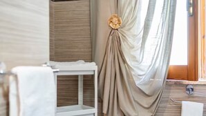 A bathroom with a wooden vanity, a white shelf, and a curtain with a floral decoration. - Luna e Stelle B&B (Sangineto)