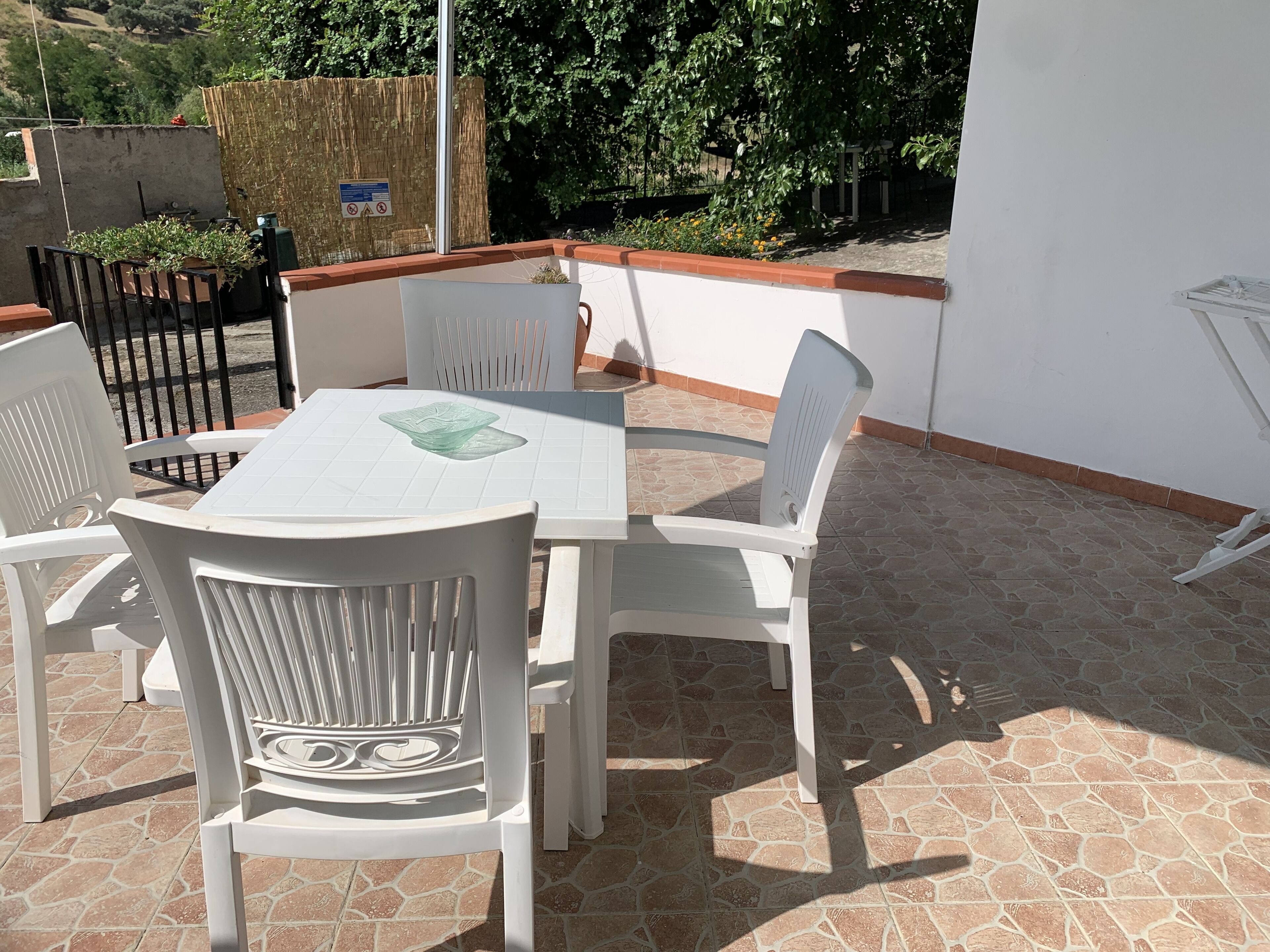 Une terrasse avec une table et des chaises, une clôture en bois et une vue sur la verdure.