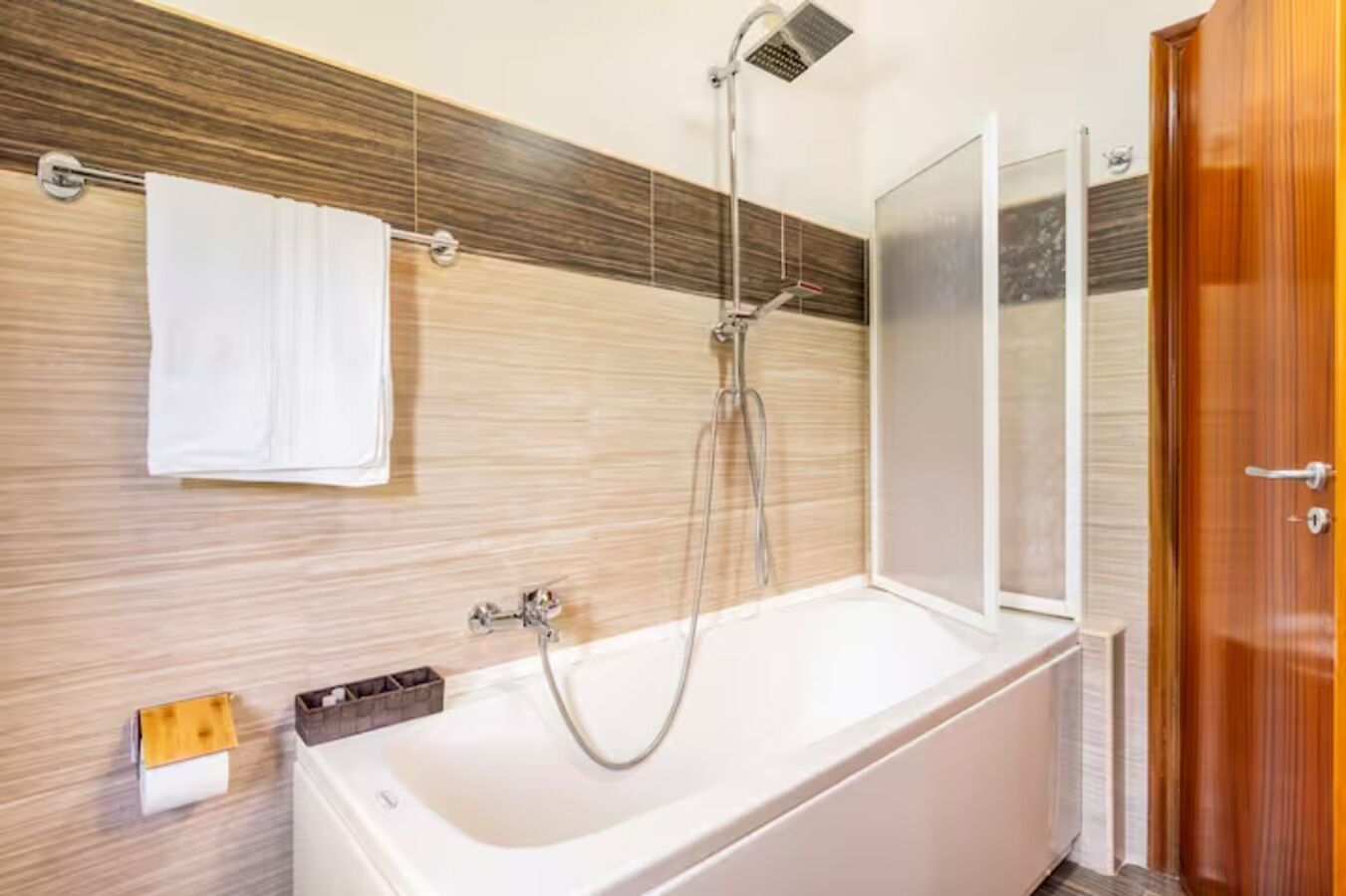 Ein modernes Badezimmer mit einer Badewanne, Dusche und einem Holzkosmetikschrank.