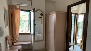 A bedroom with a bed, a desk, a chair, a wardrobe, and a bathroom visible through an open door. - Luna e Stelle B&B (Sangineto)