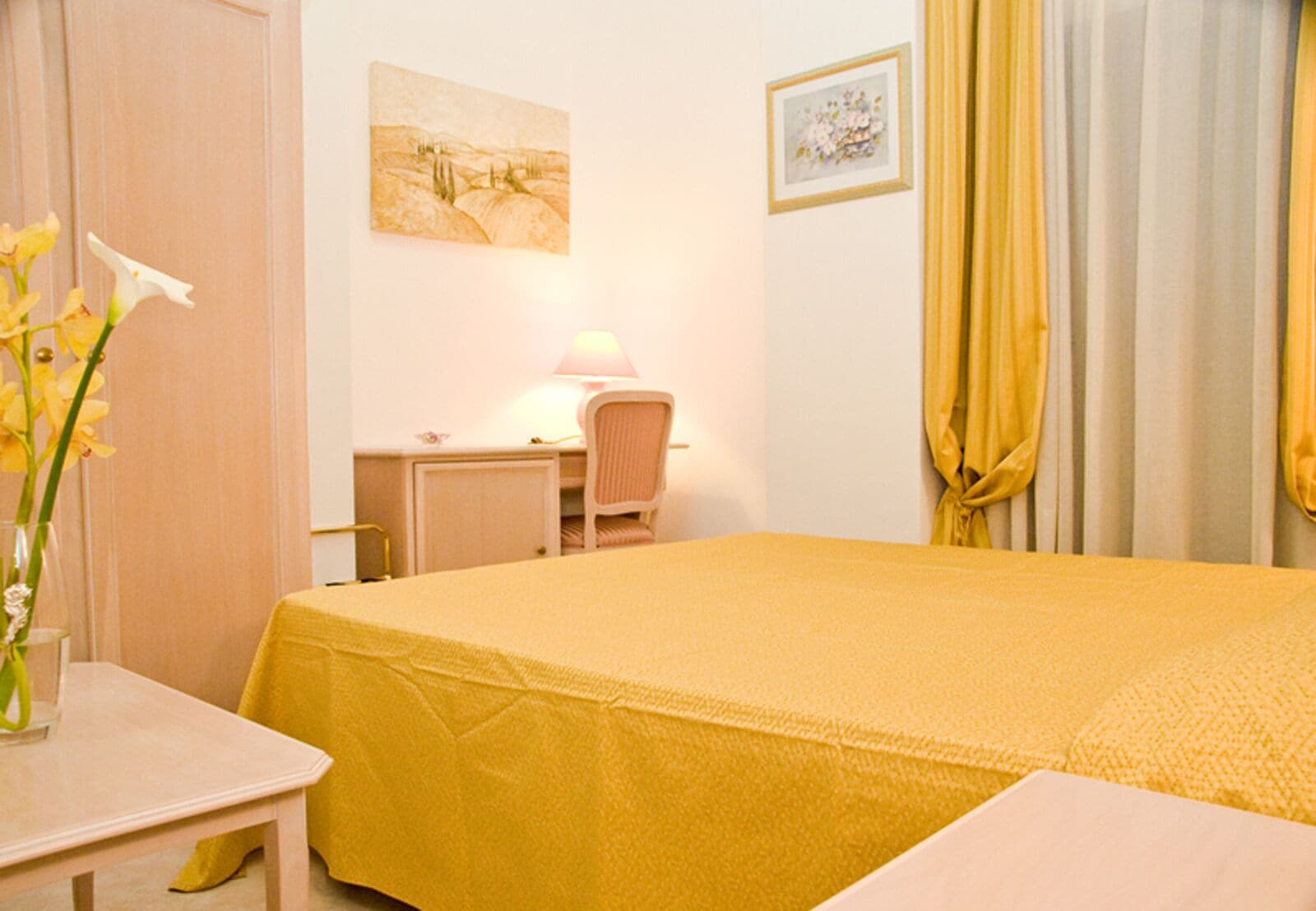 Une chambre d’hôtel avec un lit, un bureau, une chaise, une lampe et un tableau au mur.
