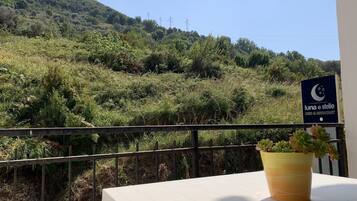 A balcony with a view of a lush green hillside and a sign for 'Luna e Stelle Bed & Breakfast'.