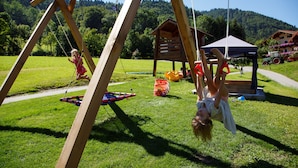 A wooden swing set in a grassy area with a wooden structure in the background. - 8. vacation apartment Edelweiss, 45sqm, terrace, kitchen, 1 bedroom, 1 living room (Ruhpolding)