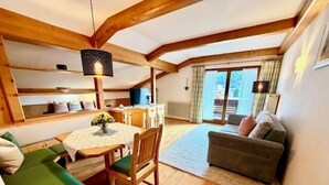 Ein gemütliches Zimmer mit Esstisch, Stühlen, einer Couch und einem Fenster.