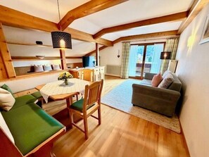 Ein gemütliches Zimmer mit Esstisch, Stühlen, einer Couch und einem Fenster.