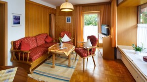 A cozy room with a wooden sofa, a dining table, and a TV. - Ferienwohnung -3- (35qm), Terrasse, Küche extra, 1 Schlaf- und 1 Wohnzimmer, max 2 Personen (Ruhpolding)