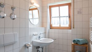 A bathroom with a toilet, sink, mirror, and window. - Ferienwohnung I° extra Schlafzimmer, Süd-Terrasse, 65 qm° (Aschau im Chiemgau)