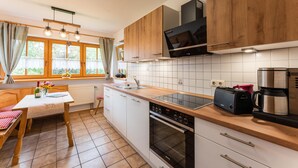 A kitchen with wooden cabinets, a built-in oven, a microwave, and a coffee maker. - Ferienwohnung I° extra Schlafzimmer, Süd-Terrasse, 65 qm° (Aschau im Chiemgau)
