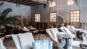 A spa room with wooden loungers, a hanging chair, and a large blue woven bag. - Apartment Montana for 2 persons and east-facing balcony, 40 sqm (Bad Reichenhall)