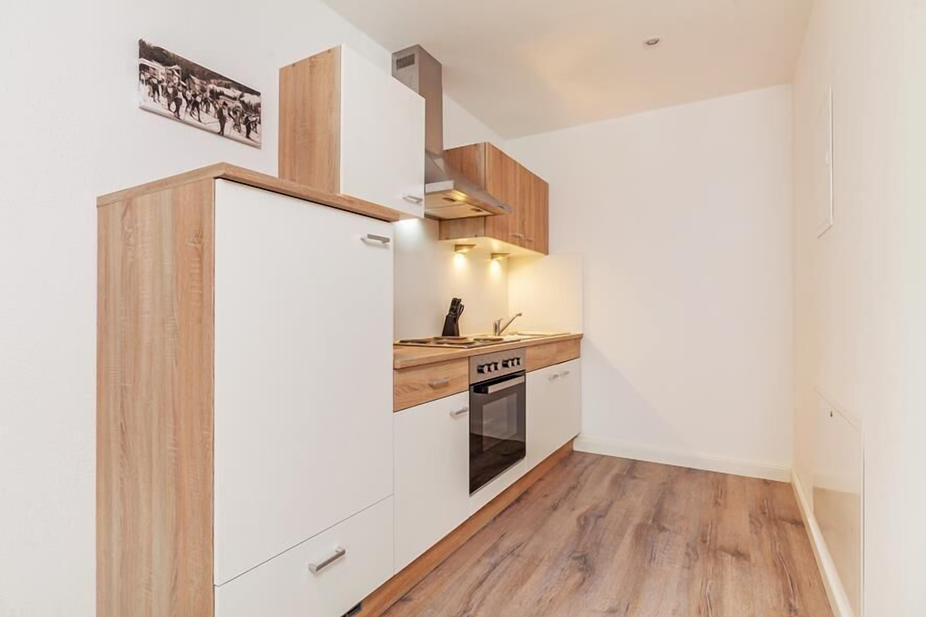 A modern kitchen with white cabinetry, a wooden countertop, and a built-in oven.