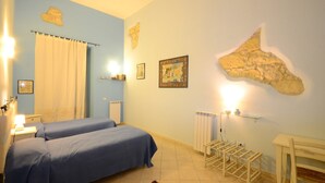 A bedroom with two beds, a radiator, a shelf with books, and a map on the wall. - B&B Su Niu (Cagliari)
