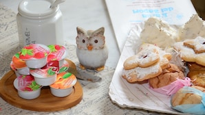 A table with various food items including cupcakes, cookies, and a decorative owl figurine. - B&B Su Niu (Cagliari)