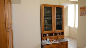 A kitchen with wooden cabinets, a countertop with various items, and a window with a view. - B&B Su Niu (Cagliari)