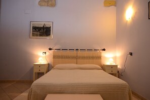 A bedroom with a bed, two bedside tables, a wall-mounted light, and a framed picture. - B&B Su Niu (Cagliari)