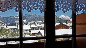 A window with a view of a snowy village, houses, and mountains. - Apartment- 3 persons, 50sqm, 1 bedroom, balcony, WLAN (Oberwössen)